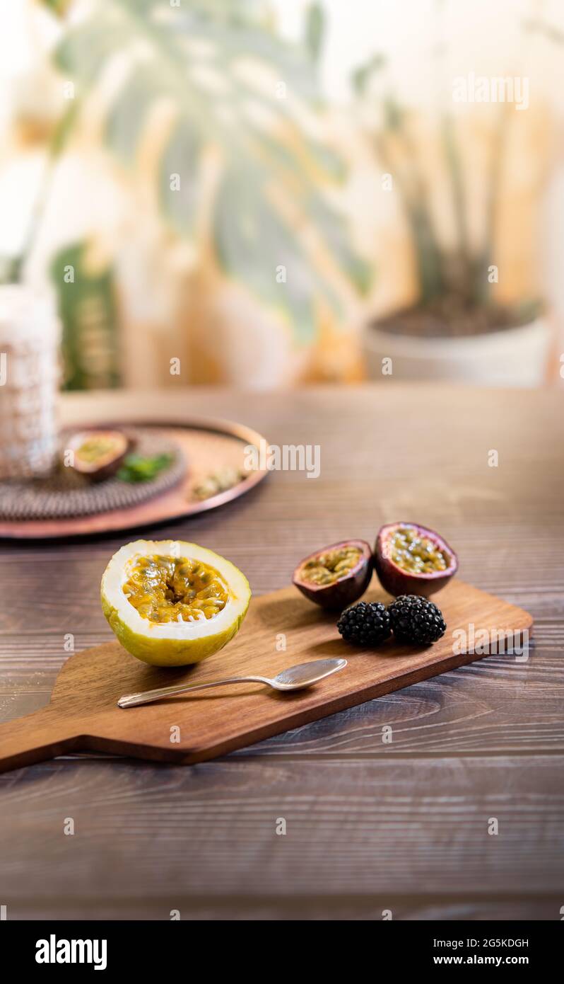 Moody scuro fotografia alimentare closeup di un frutto di passione maracuya con more. Concetto di cibo naturale e sano. Foto Stock