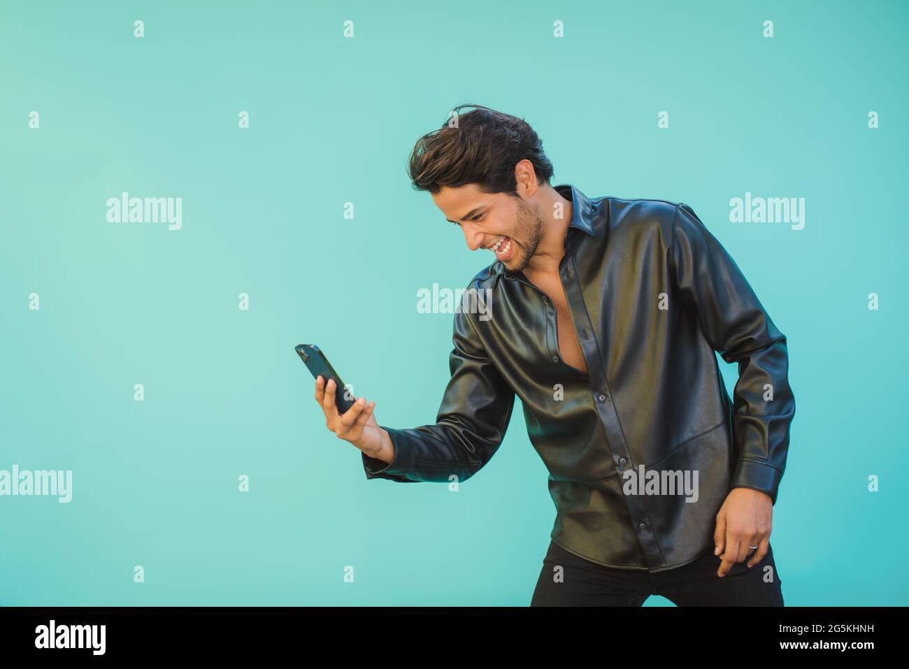 Uomo di contenuti che prende selfie sullo smartphone mentre si appoggia in avanti Foto Stock