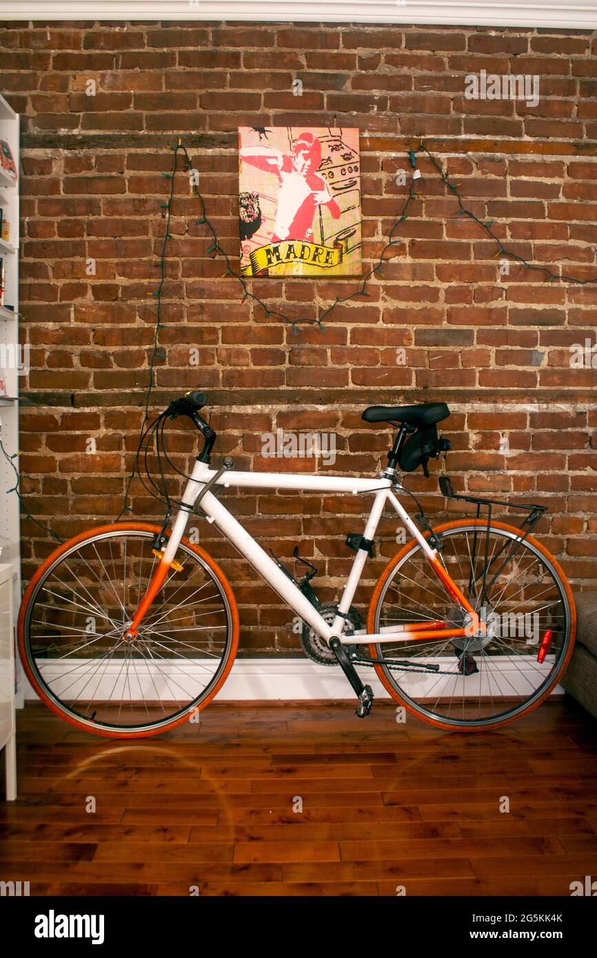 Bicicletta colorata appoggiata al muro di mattoni di una stanza con luci di natale strinzate lungo il muro Foto Stock