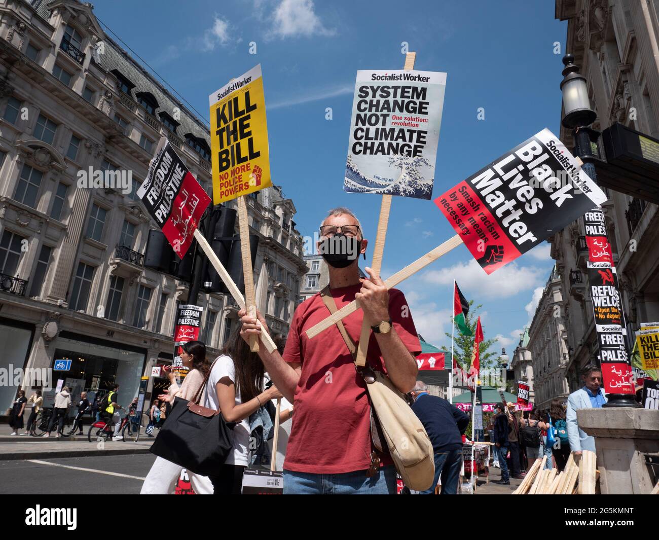 Proteste di Londra, attivisti protestano nel centro di Londra alla dimostrazione nazionale dell'Assemblea popolare, uomo che tiene vari cartelli, Kill the Bill, cambiamento di sistema non cambiamento climatico, la questione delle vite nere e la libertà per la palestina, tutti fatti da Socialist Worker Foto Stock