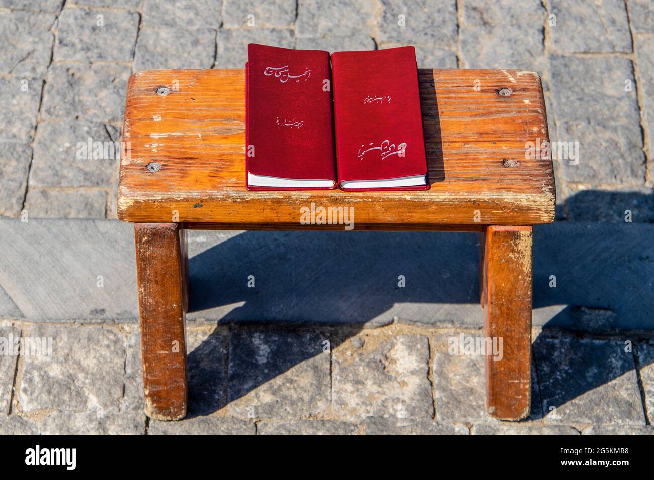 Due koran seduti su un tavolo di legno grugnoso su una superficie di ciottoli al sole con ombra. Foto Stock