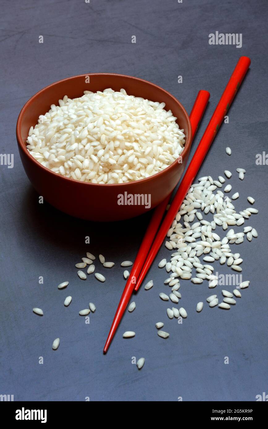 Riso bianco, grani di riso in recipiente con bastoncini Foto Stock