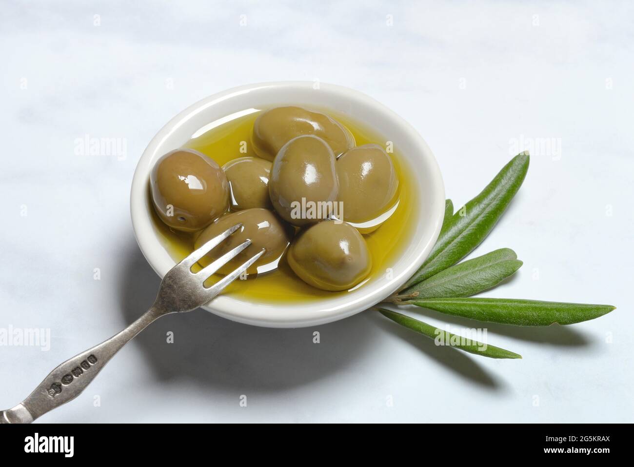 Olive verdi in ciotola con olio d'oliva Foto Stock