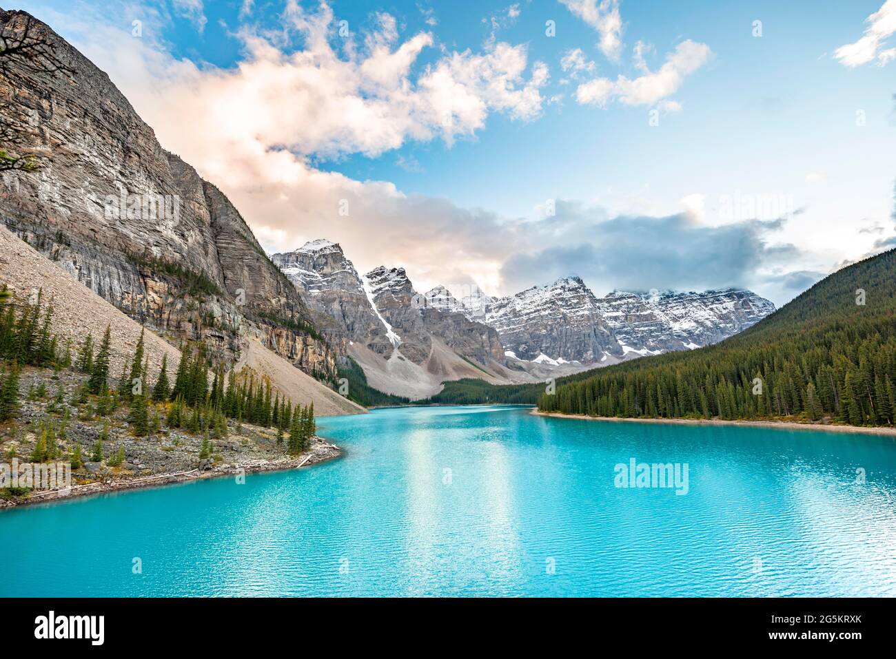 Nuvole che pendono tra le cime delle montagne, catena montuosa dietro il lago glaciale turchese, alba, lago Moraine, Valle dei dieci picchi, Montagne Rocciose, Foto Stock