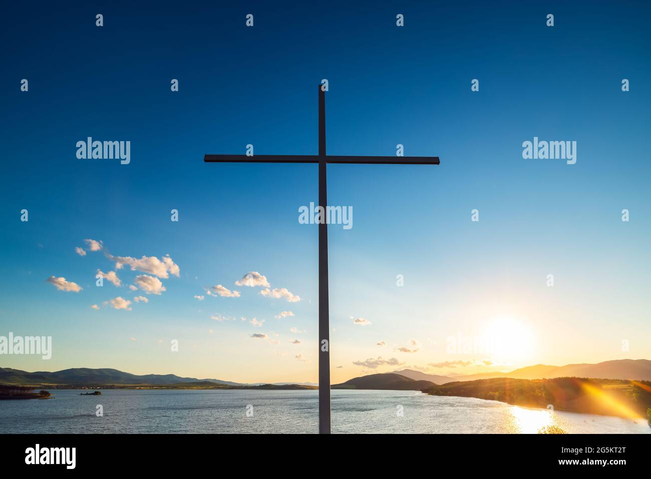 Croce cristiana contro le nuvole e il lago Foto Stock