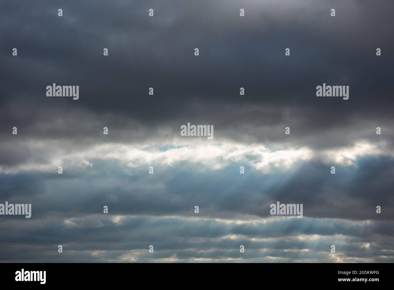 Splendido paesaggio cielo con strisce di grigio scuro pesante, nuvole quasi nere tempestose. Raggi solari testurizzati chiaramente visibili attraverso gli spazi vuoti. Alcuni c Foto Stock