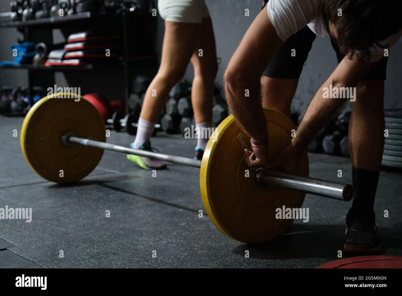 Giovane uomo che regola il disco del peso al bar in una palestra con crossfit. Foto Stock