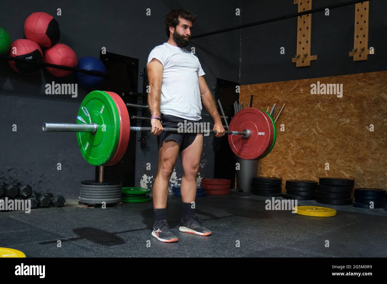 Giovane uomo barbuto che fa deadlift esercizio in una palestra crossfit. Foto Stock