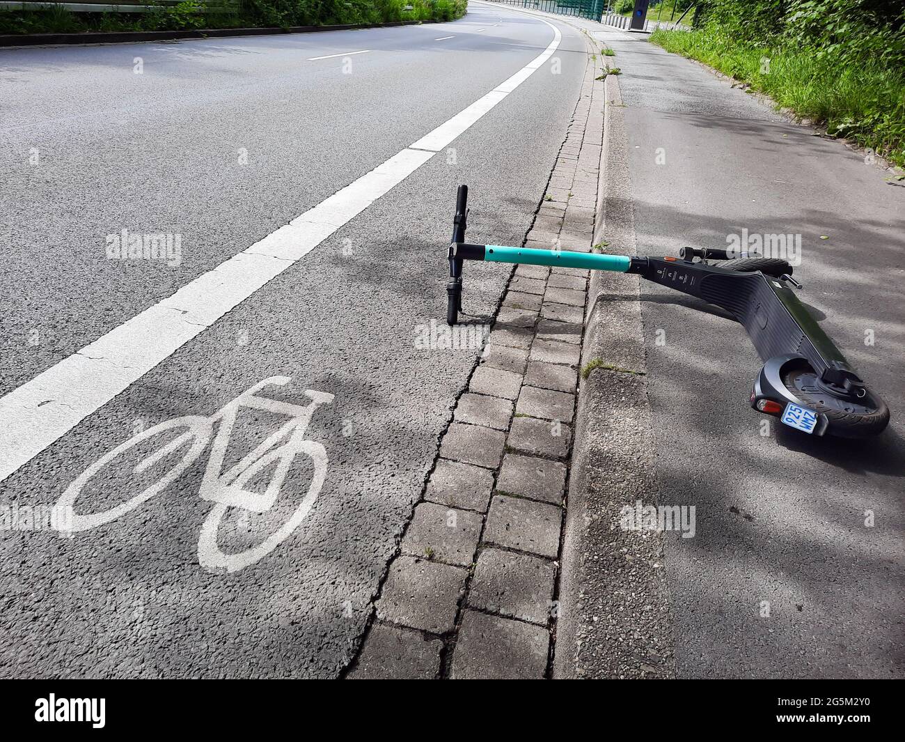 Un e-scooter gettato incautamente è in parte su una pista ciclabile a Dortmund, Germania --- Ein achtlos hingeworfener e-Scooter liegt teilweise auf einem Radweg a Dortmund, Germania Foto Stock