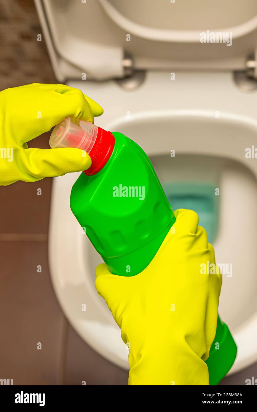 Pulizia e disinfezione dei servizi igienici. Aprire il detergente per wc  prima dell'uso. Una mano con guanti pulisce il gabinetto con un  disinfettante Foto stock - Alamy
