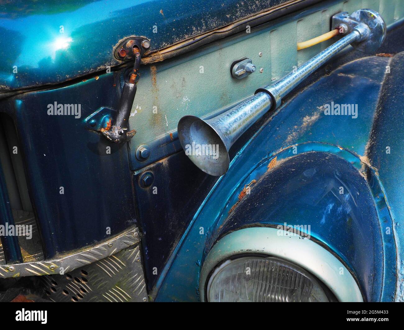 Frammento di auto blu brillante retro con un clacson esterno e schizzato di sporcizia. Foto di primo piano Foto Stock