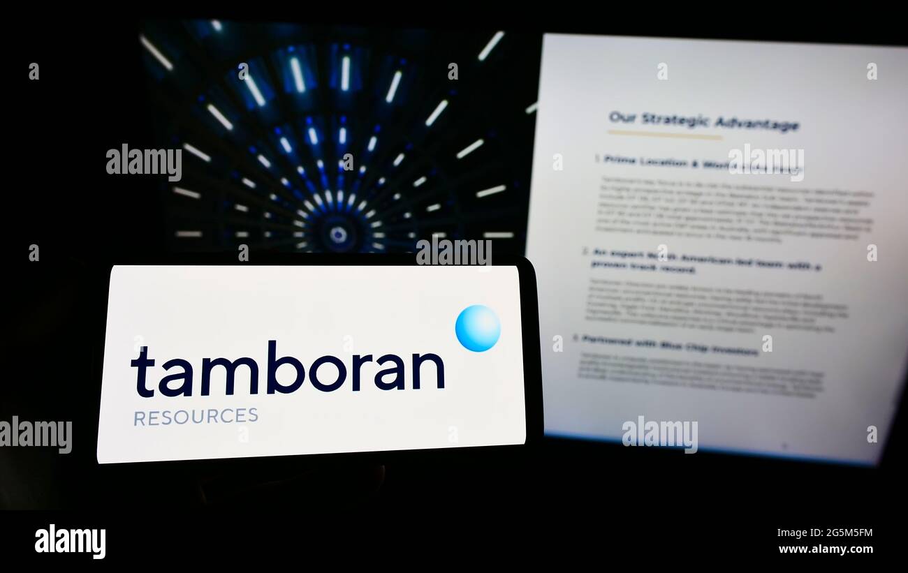 Persona che detiene smartphone con il logo della società energetica australiana Tamboran Resources Limited sullo schermo di fronte al sito web. Mettere a fuoco il display del telefono. Foto Stock