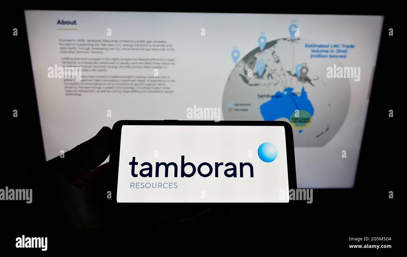 Persona che tiene il telefono mobile con il logo della società australiana di energia Tamboran Resources Limited sullo schermo di fronte alla pagina web. Mettere a fuoco il display del telefono. Foto Stock