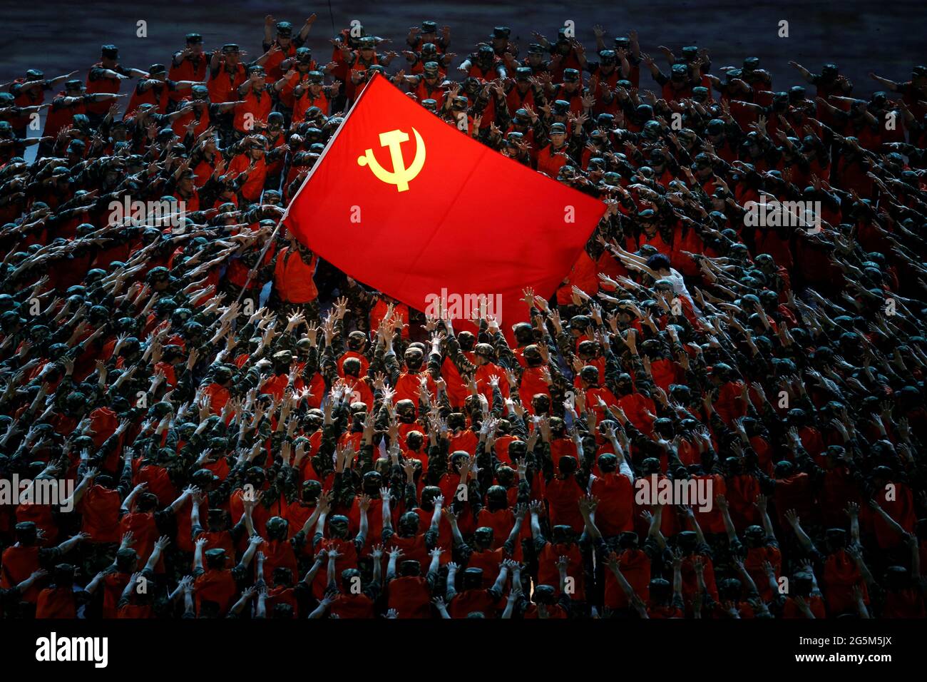 Gli artisti si esibiscono intorno alla bandiera rossa durante uno spettacolo commemorativo del centesimo anniversario della fondazione del Partito comunista cinese allo Stadio Nazionale di Pechino, Cina, 28 giugno 2021. REUTERS/Thomas Peter Foto Stock