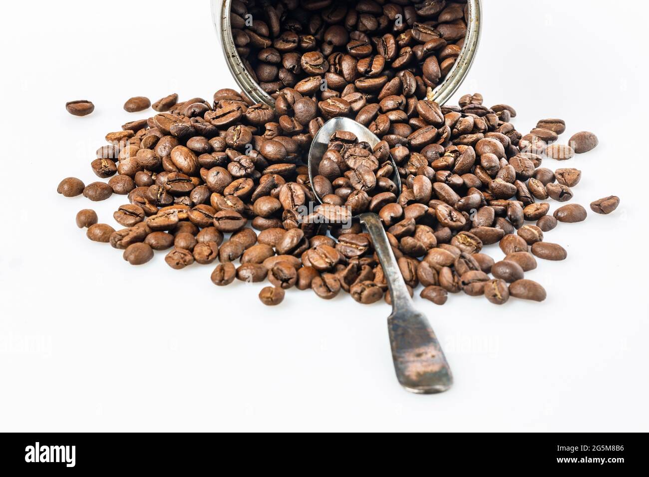 Lattina aperta e grani di caffè nero su sfondo bianco. Fagioli arabica arrostiti profumati su un tavolo bianco. Bevanda tradizionale del mattino. Spazio di copia. Foto Stock