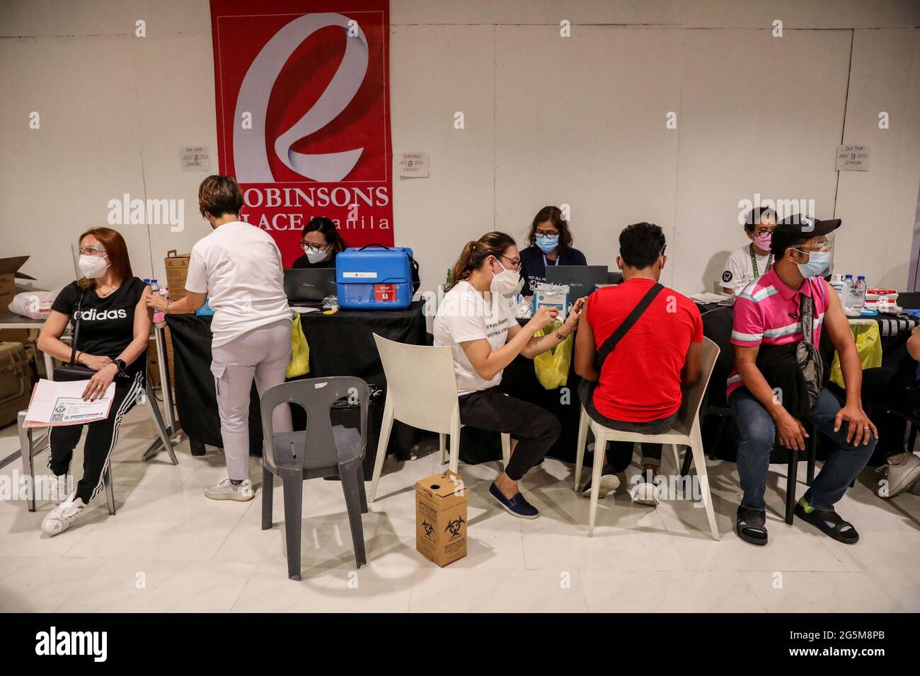 Gli operatori sanitari inoculano i pazienti con il vaccino Sinovac COVID-19 all'interno di un centro commerciale trasformato in un sito di vaccinazione a Manila, Filippine. Foto Stock