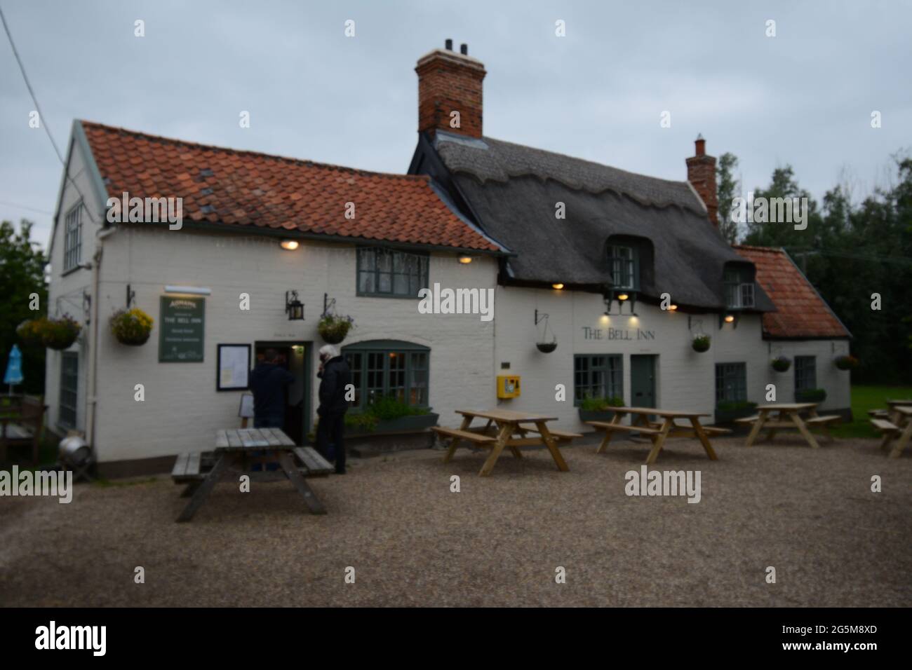 Il Bell Inn Public House o pub con tetto in paglia e panchine con cestini appesi vecchio segno pub segni ghiaia bere fuori cestini appesi Foto Stock