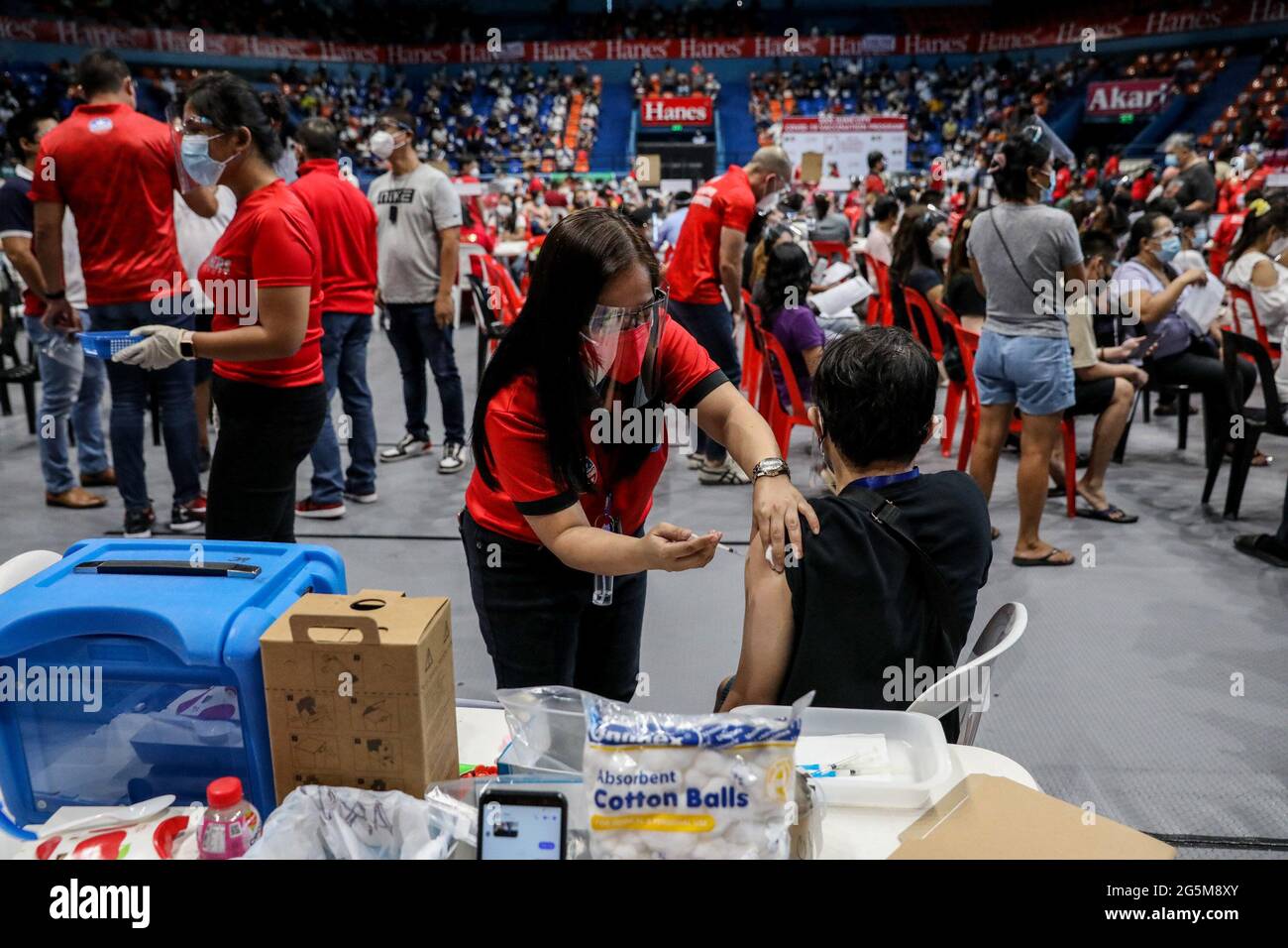 Un operatore sanitario inocula un paziente con il vaccino COVID-19 Pfizer-BioNTech all'interno di uno stadio sportivo trasformato in un sito di vaccinazione temporanea a San Juan City, Metro Manila, Filippine. Foto Stock