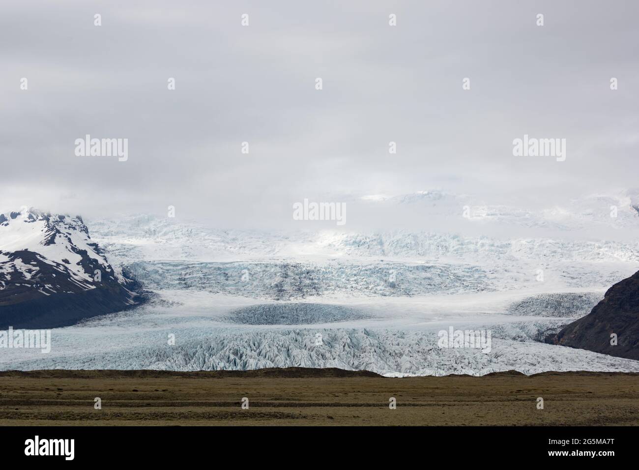 La luce drammatica cade sul bordo di un ghiacciaio di uscita incanalato da Vatnajokull nel sud dell'Islanda. Foto Stock