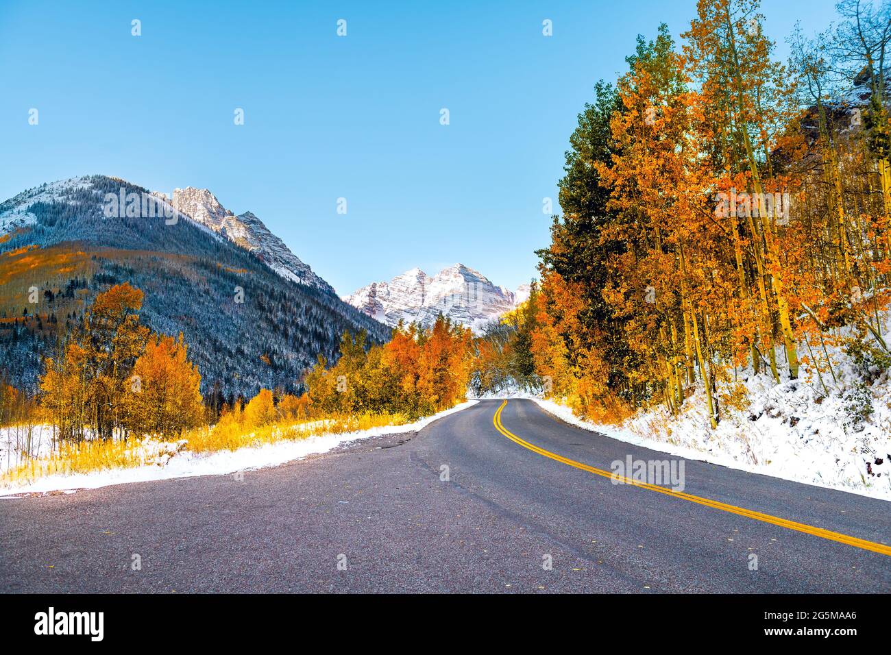 Maroon Bells picco vista dell'alba ad Aspen, Colorado montagna rocciosa e autunno giallo fogliame vista e inverno neve congelati alberi su strada Creek viaggio Foto Stock