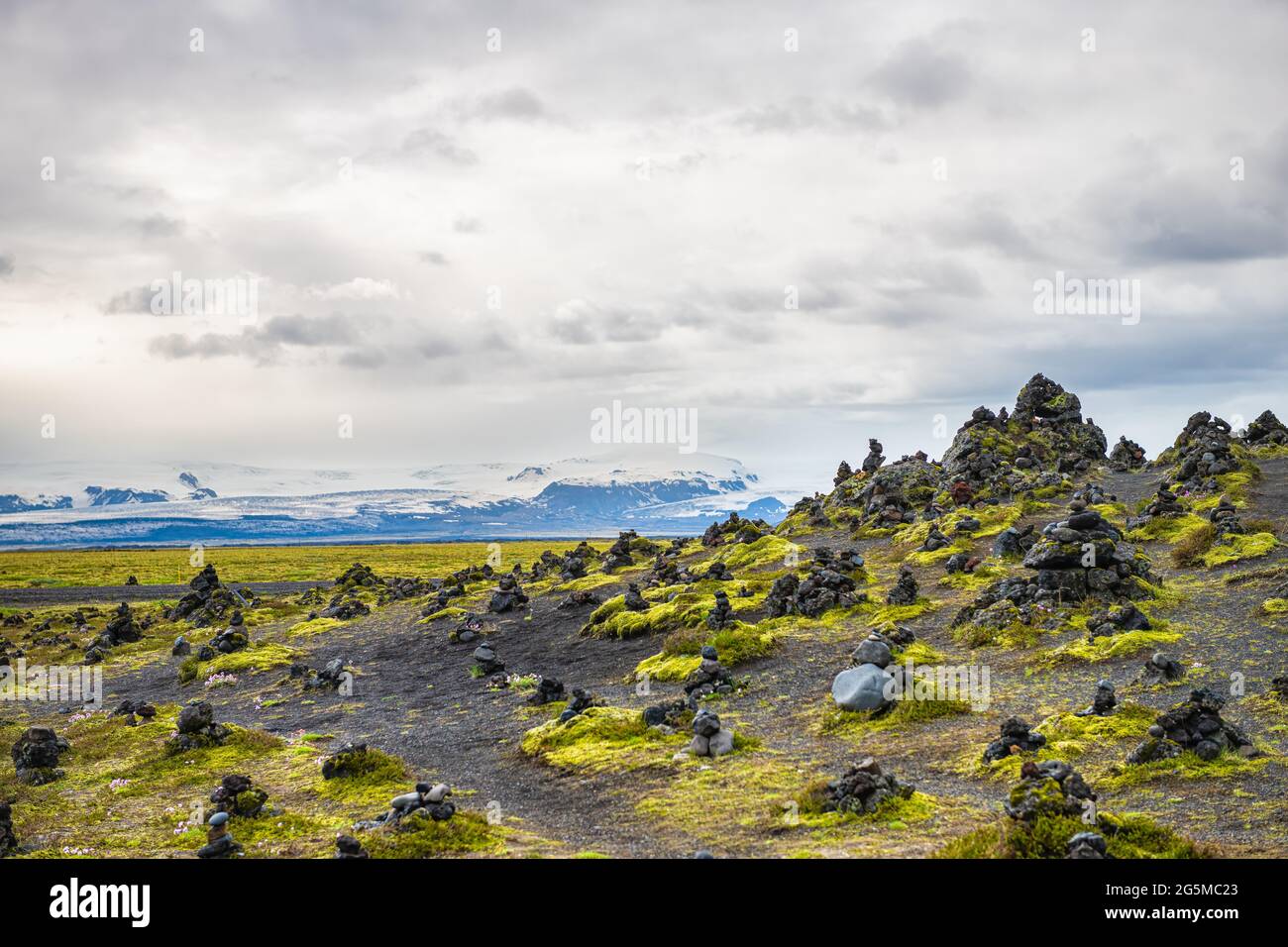 Laufscalavarda, Islanda estate paesaggio montagne e pietra cairns con muschio verde e sfondo di montagne innevate Foto Stock
