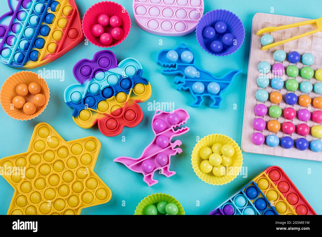 Set di giocattoli trendy e colorati fidget pop esso e clip di legno beads gioco da tavolo su sfondo blu. Nuovi giocattoli sensoriali anti-stress e logica di pensiero per chi Foto Stock