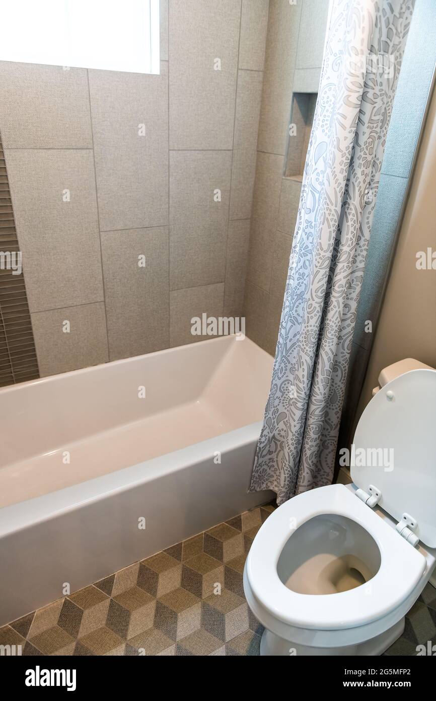 Interni moderni del bagno con vasca doccia piastrellata decorativa in casa contemporanea, appartamento o casa con servizi igienici e tende Foto Stock