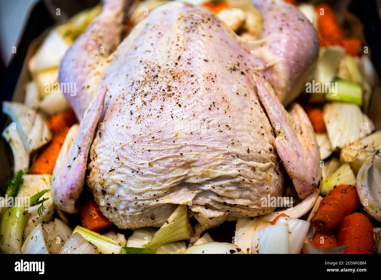 Crudi pollo intero crudo croccato di pelle con consistenza su vassoio da forno con carote di finocchio verdure e pepe nero condimento su uccello Foto Stock