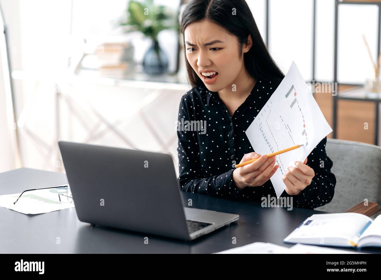 Infastidito dirigente di affari di donna asiatica arrabbiato, conduce una riunione con i colleghi in linea, parlando con una videochiamata, scolding per i risultati scarsi, mostrando il rapporto finanziario, umore negativo e irritato Foto Stock