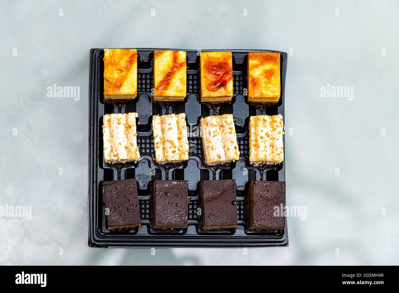 Closeup di una dozzina di fette di torta con caffè opera, lampone e pasticceria al cioccolato in vendita in Francia piatto piano superiore vista Foto Stock