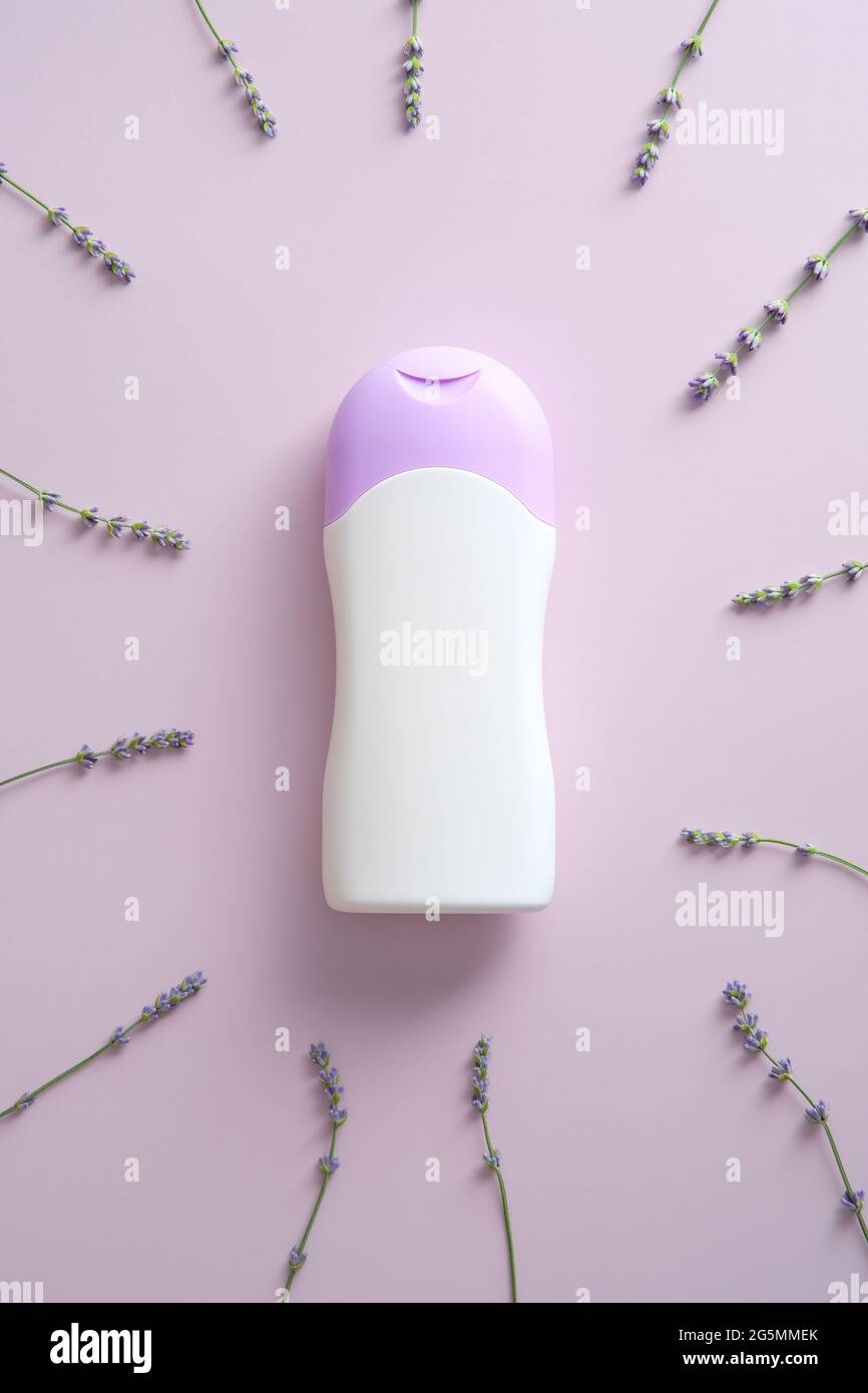 Mokup naturale del biberon prodotto per la cura dei capelli con lavanda su sfondo viola. Shampoo alle erbe. Foto Stock