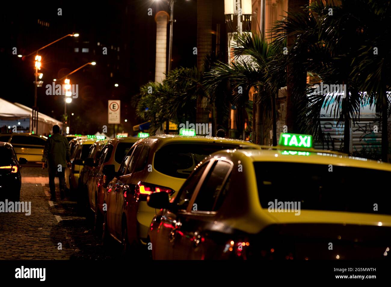 Sud America, Brasile: Coda di taxi sul lato del Teatro Municipale nel centro di Rio de Janeiro di notte. Cartelli per taxi illuminati. Cabine parcheggiate in fila. Foto Stock