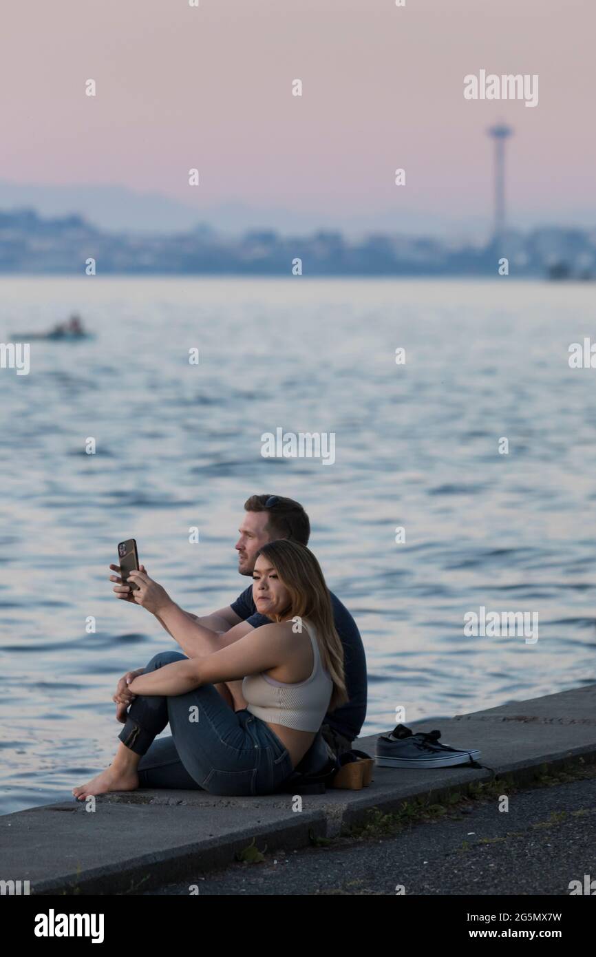 Una giovane coppia gode del tramonto all'Alki Beach Park durante un'ondata di caldo a Seattle domenica 27 giugno 2021. Il nord-ovest del Pacifico sta salterando sotto un Foto Stock