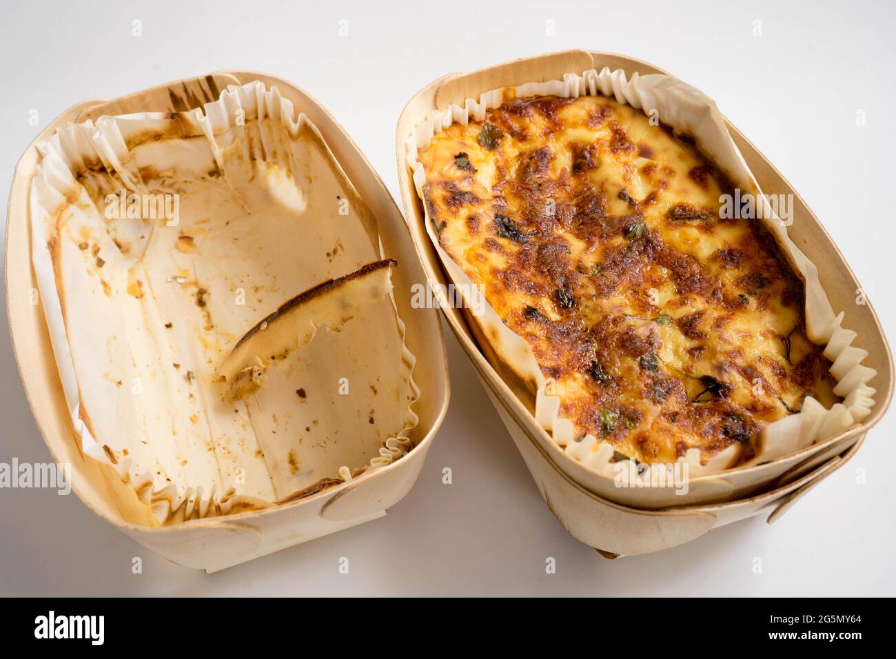 lasagne cotte al forno e contenitore vuoto di legno su fondo bianco Foto Stock
