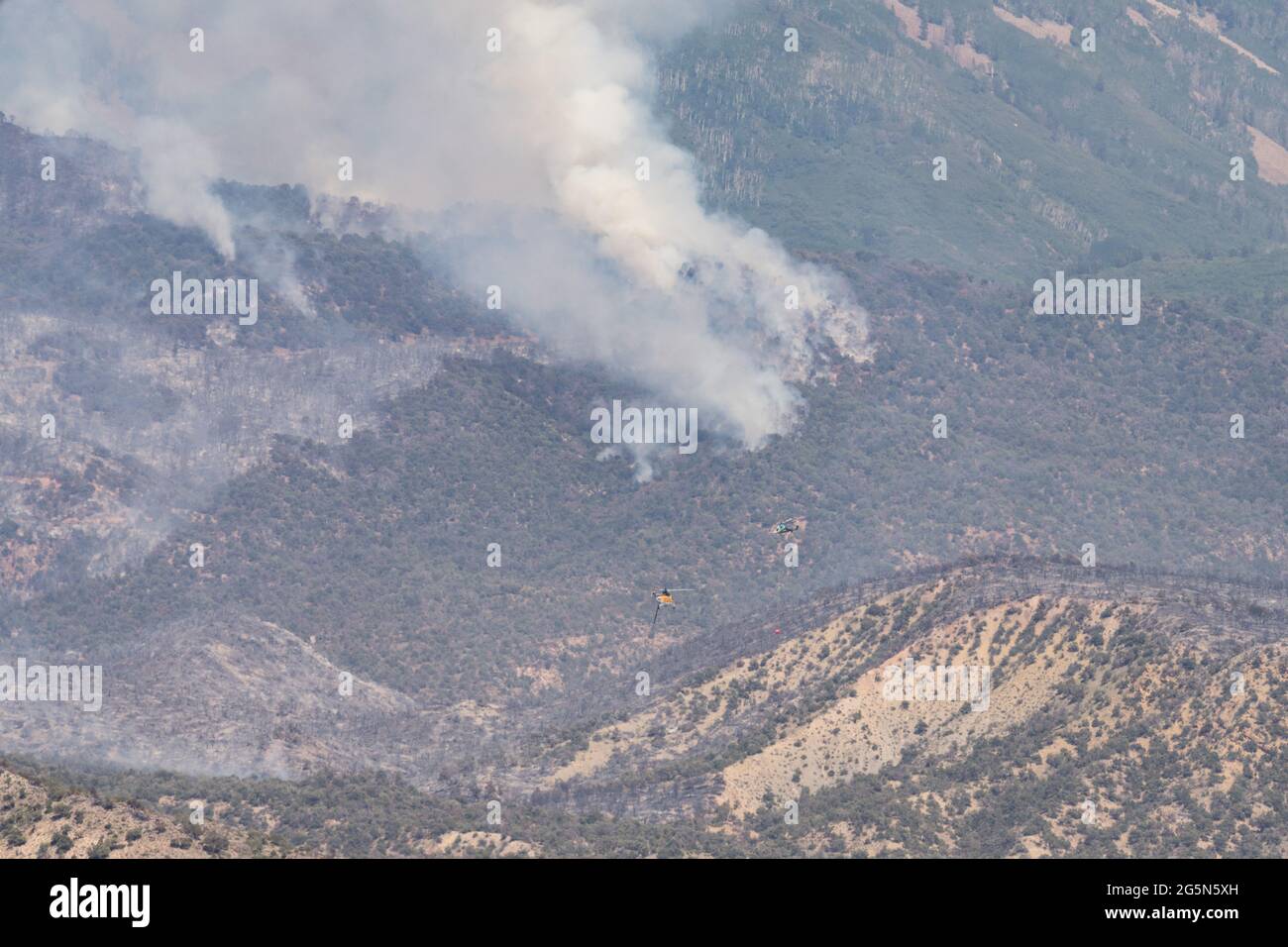 Un Sikorsky S-61 e un elicottero antincendio K-Max trasportano acqua per cadere su un fuoco di terra nelle montagne di la SAL nello Utah. Foto Stock