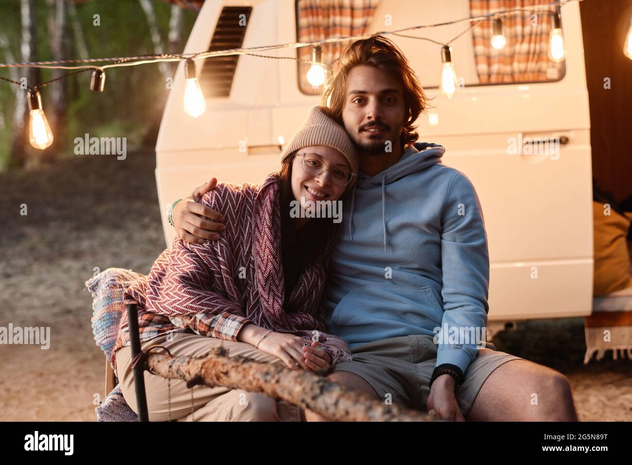 Ritratto di giovane coppia che si abbraccia e sorride alla macchina fotografica mentre si riposa insieme su un picnic Foto Stock