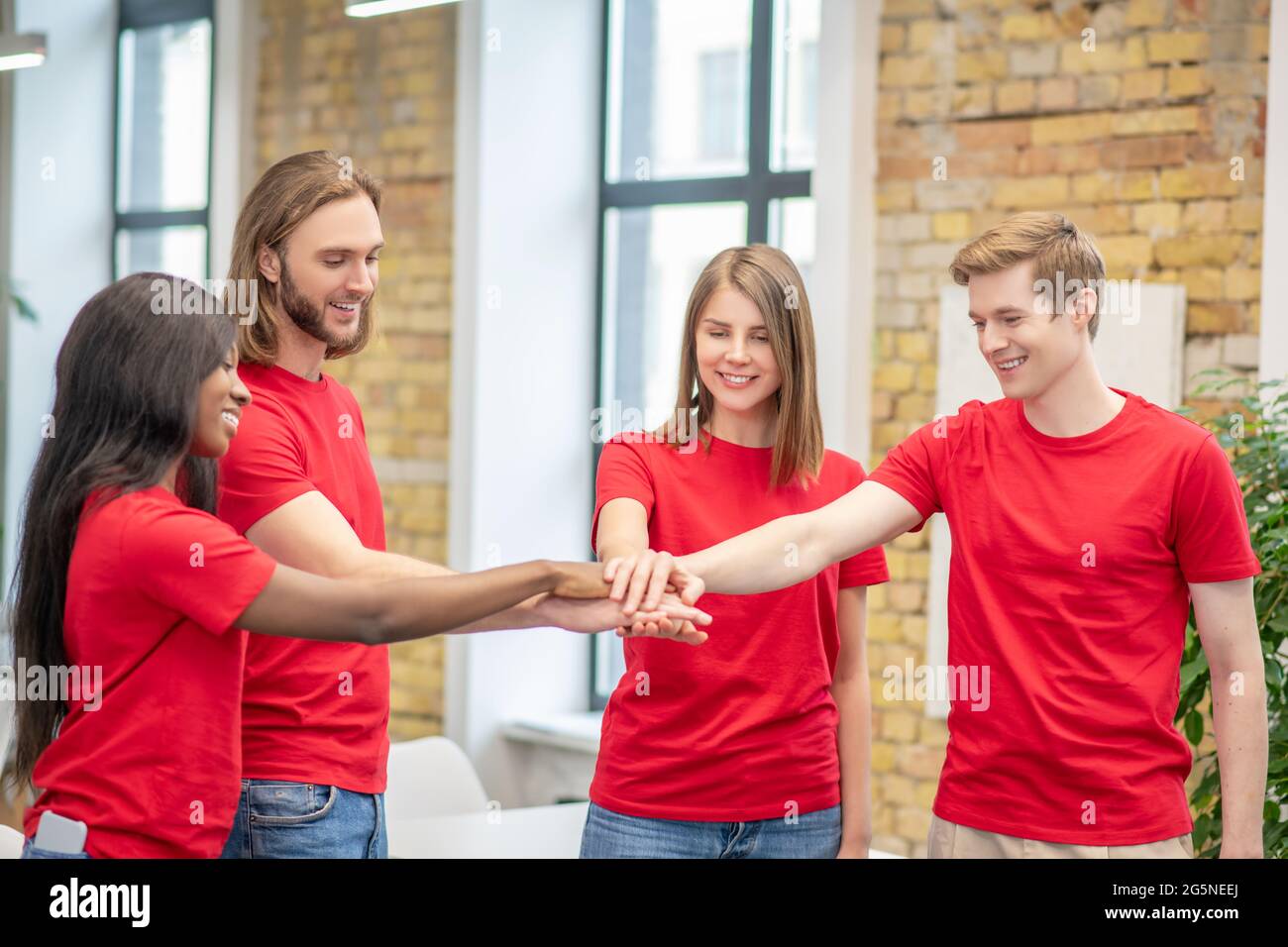 Giovani volontari gioiosi che mostrano un gesto di unità Foto Stock