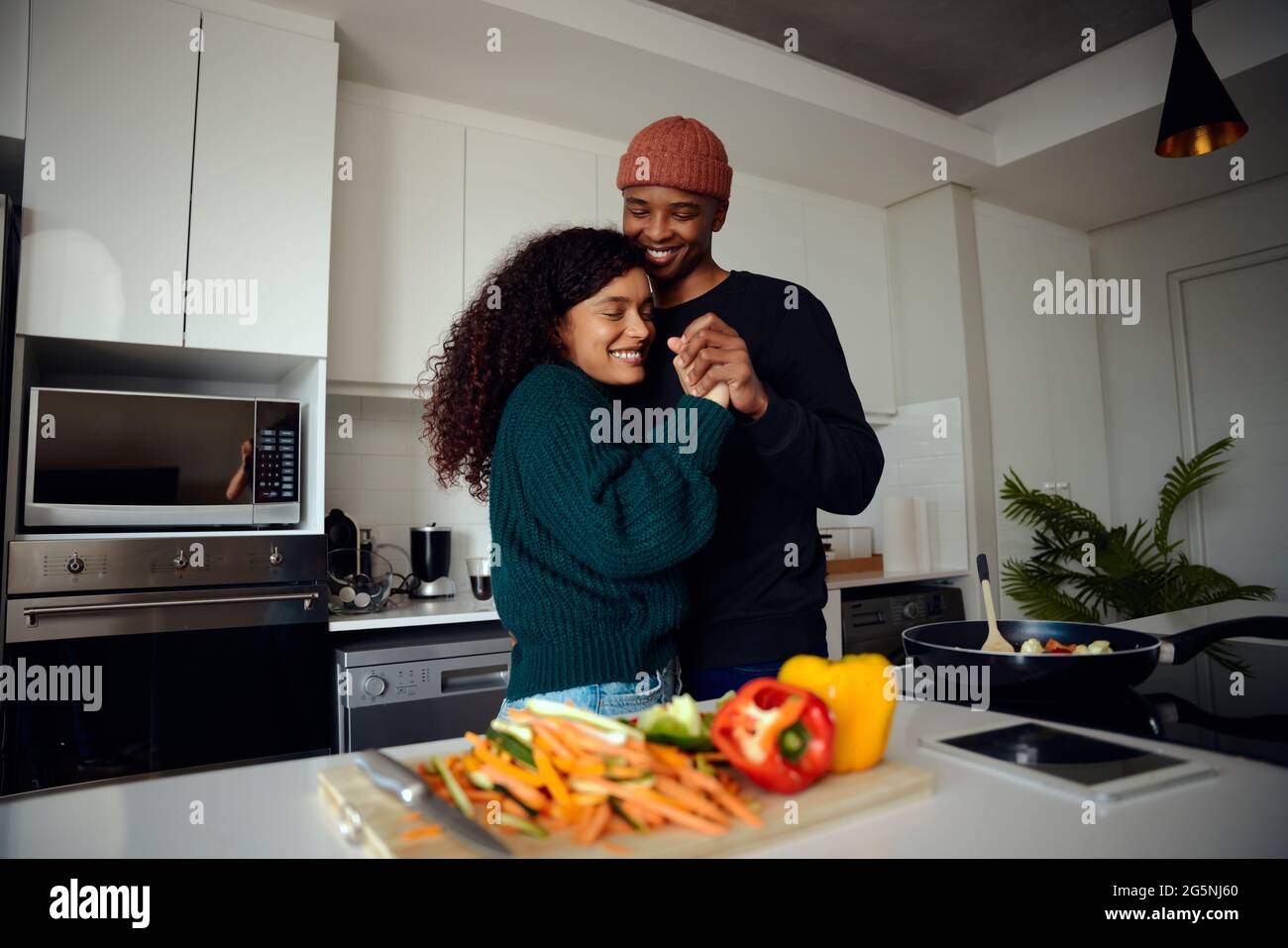 Giovane, felice coppia di gara mista che tiene le mani in cucina. Una coppia mista che balla insieme e si diverte. Foto di alta qualità Foto Stock