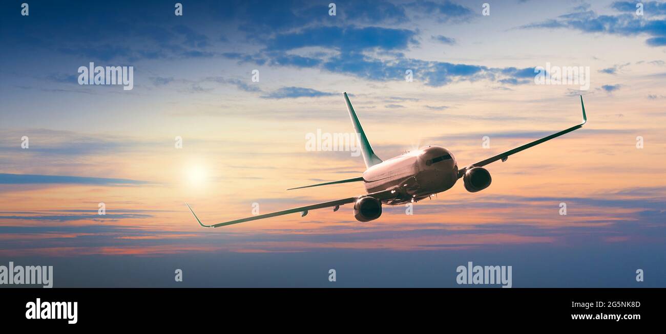 Passeggeri aerei commerciali che volano sopra le nuvole alla luce del tramonto. Concetto di viaggio veloce, vacanze e affari. Foto Stock