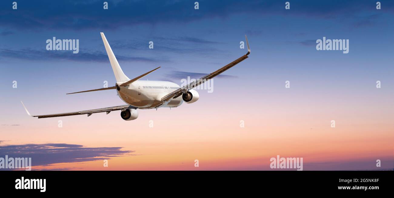 Passeggeri aerei commerciali che volano sopra le nuvole alla luce del tramonto. Concetto di viaggio veloce, vacanze e affari. Foto Stock