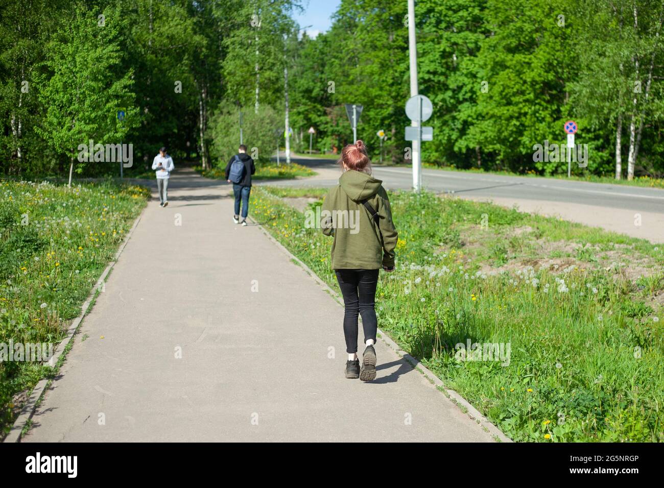 La ragazza cammina per la strada. Persone sulla strada pedonale. Parco percorso per la città. Persone senza volti. Foto Stock