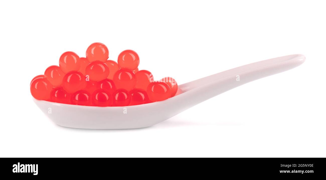 Perle di taperioca rosse per il tè delle bolle isolate su sfondo bianco. Perle di tapioca in cucchiaio di ceramica. Foto Stock