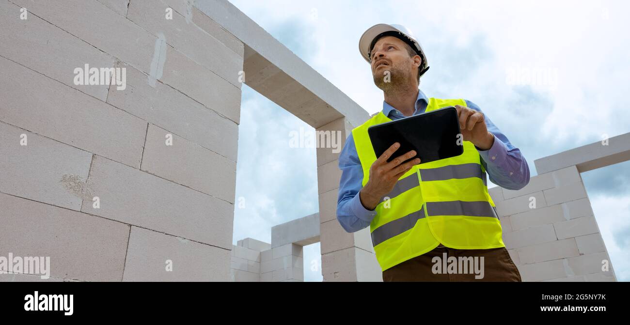 monitoraggio dei progetti di costruzione - supervisore tecnico che lavora con il tablet digitale nel cantiere. spazio di copia per striscioni Foto Stock