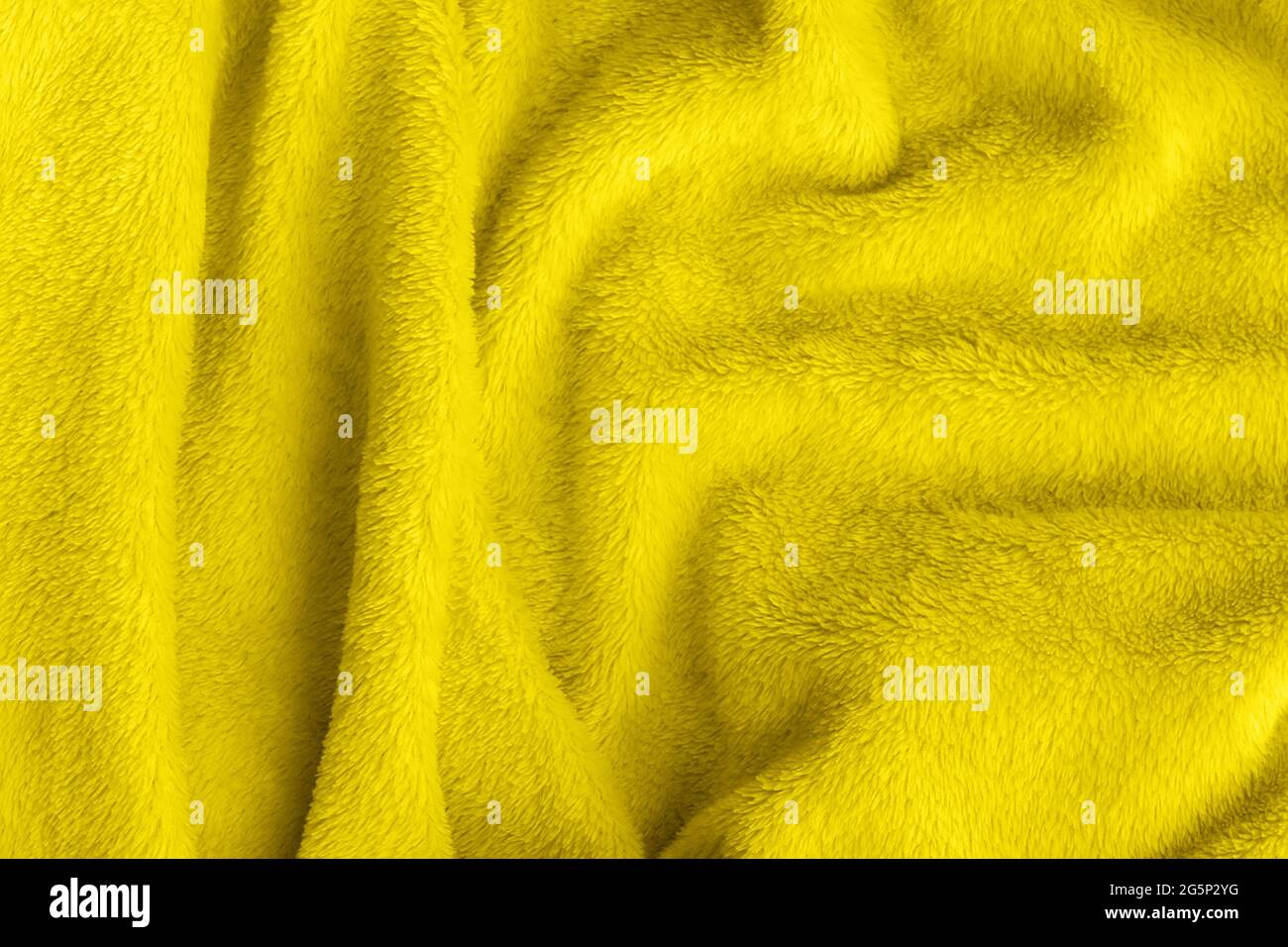 Tessuto morbido giallo illuminante. Tessuto crumpled faux fur coperta sfondo. Tendenza colore dell'anno 2021. Foto Stock