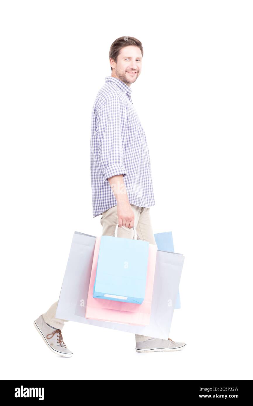 Studio ritratto scatto di giovane adulto caucasico uomo che indossa abiti casual in piedi da solo tenendo borse della spesa, sfondo bianco Foto Stock