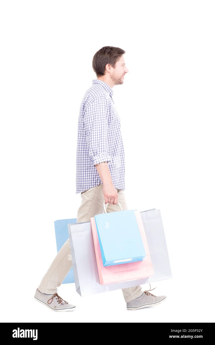 Studio ritratto scatto di giovane adulto caucasico uomo che indossa abiti casual in piedi da solo tenendo borse della spesa, sfondo bianco Foto Stock