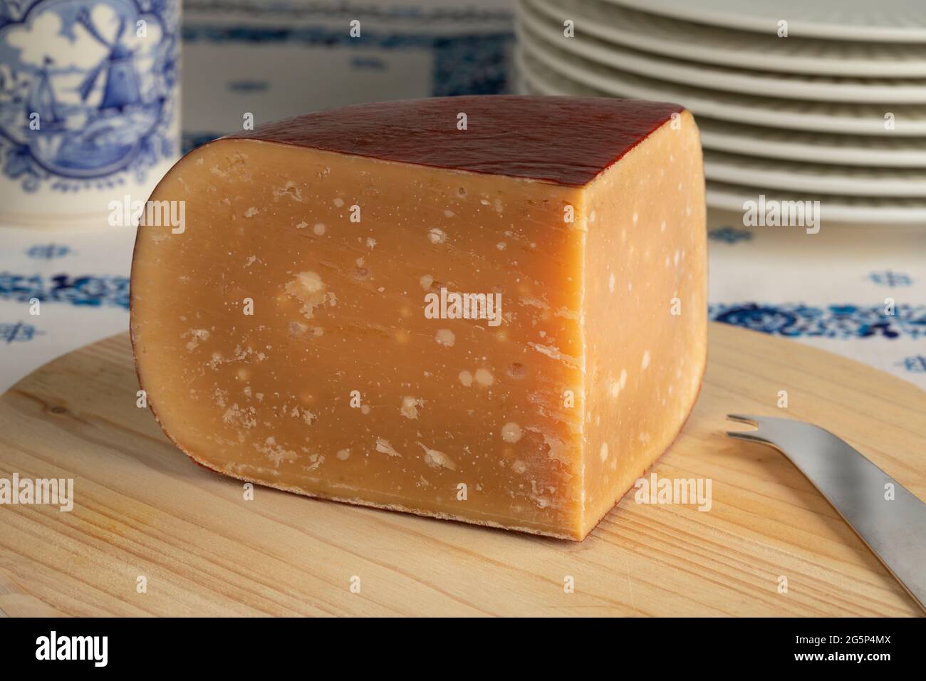 Incuneamento di vecchio formaggio di pecora olandese maturo su un tagliere Foto Stock