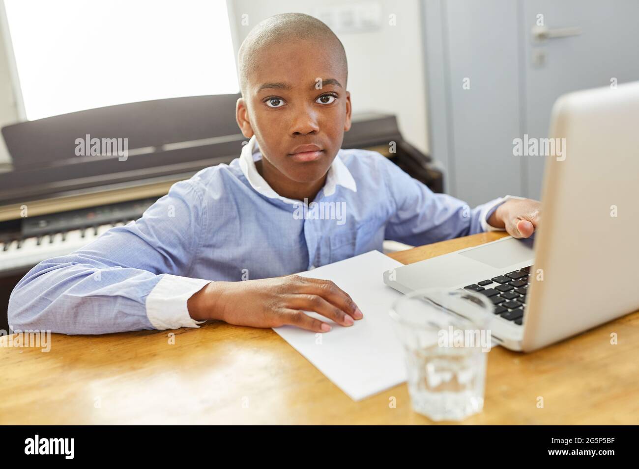 Ragazzo africano che studia online al computer portatile mentre si sta a casa Foto Stock