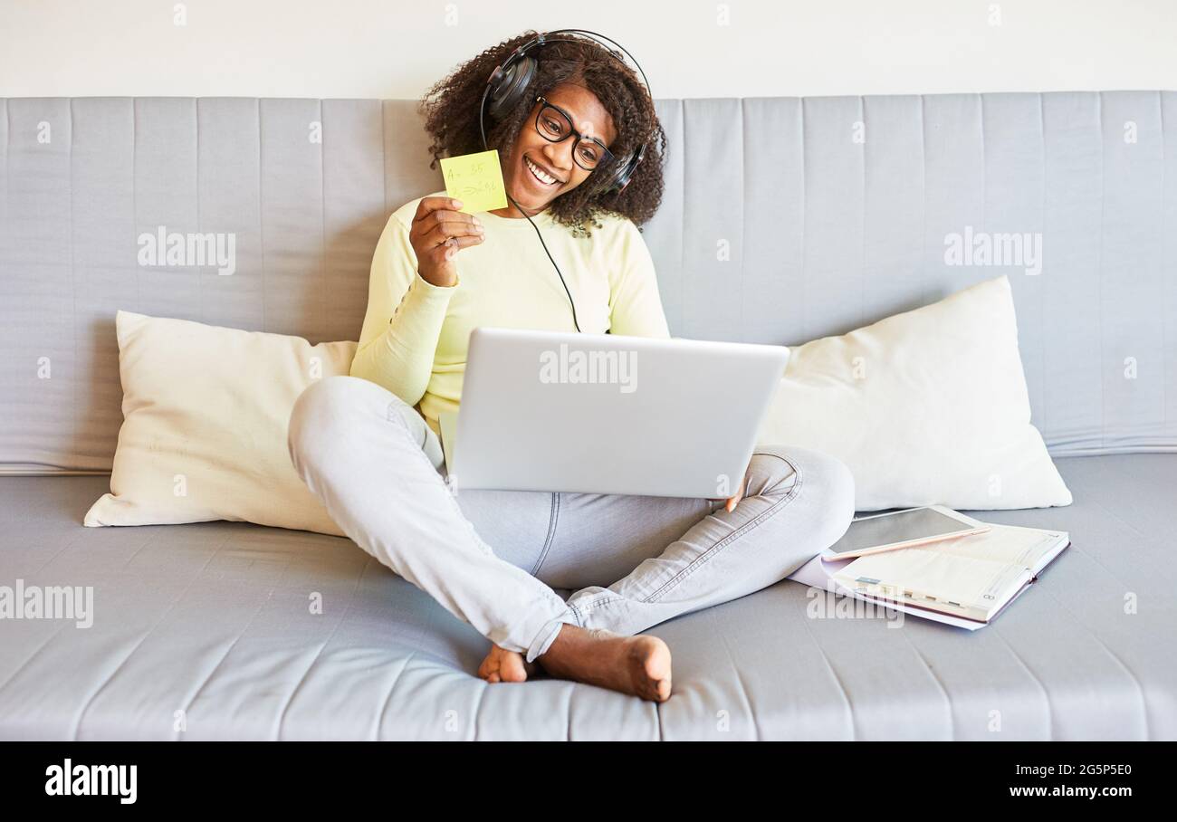 Donna africana che usa il PC portatile sul divano mentre online dating come partner di ricerca su Internet Foto Stock