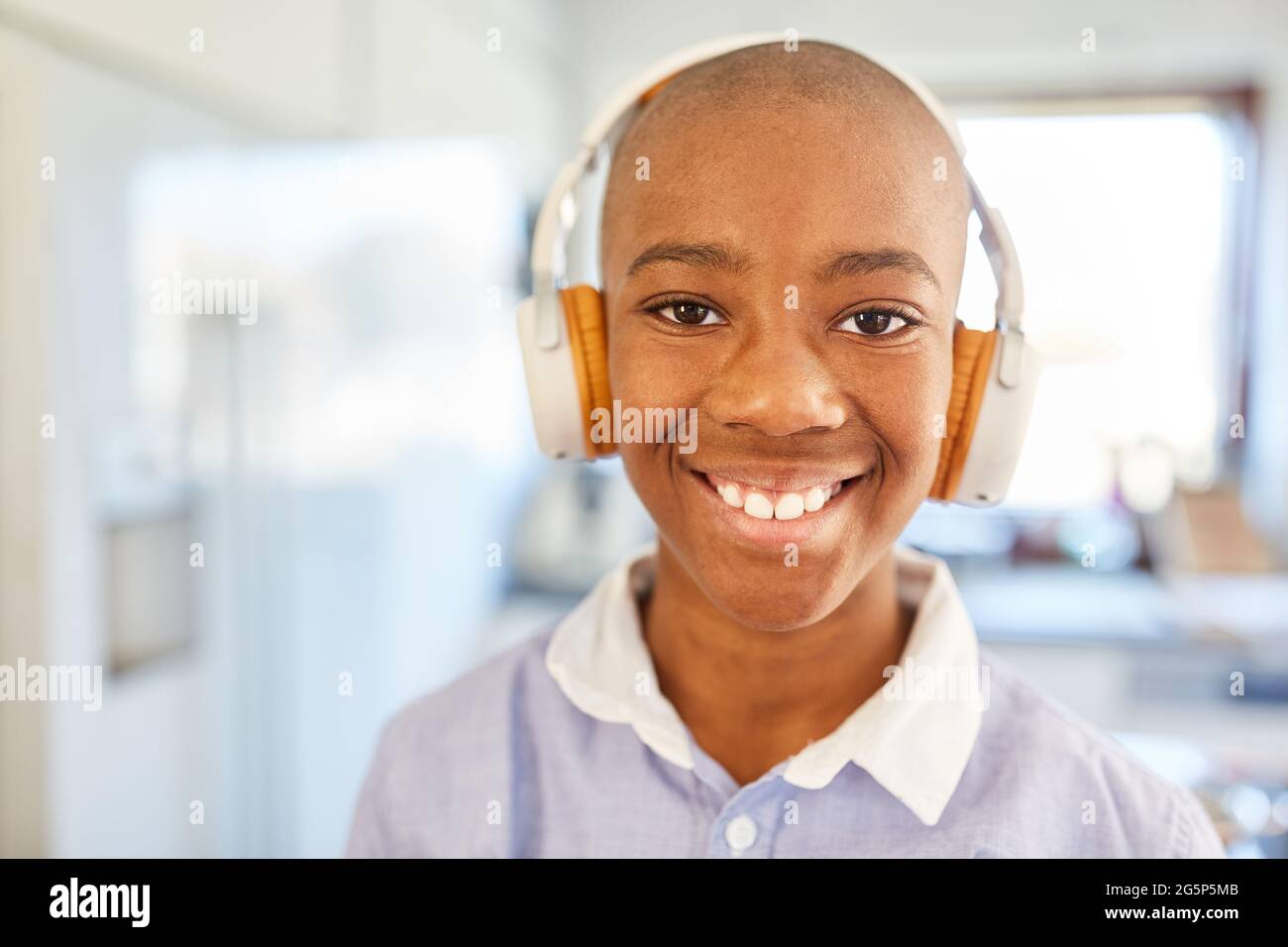 Ragazzo sorridente che indossa le cuffie durante l'ascolto di musica in streaming online o a distanza Foto Stock